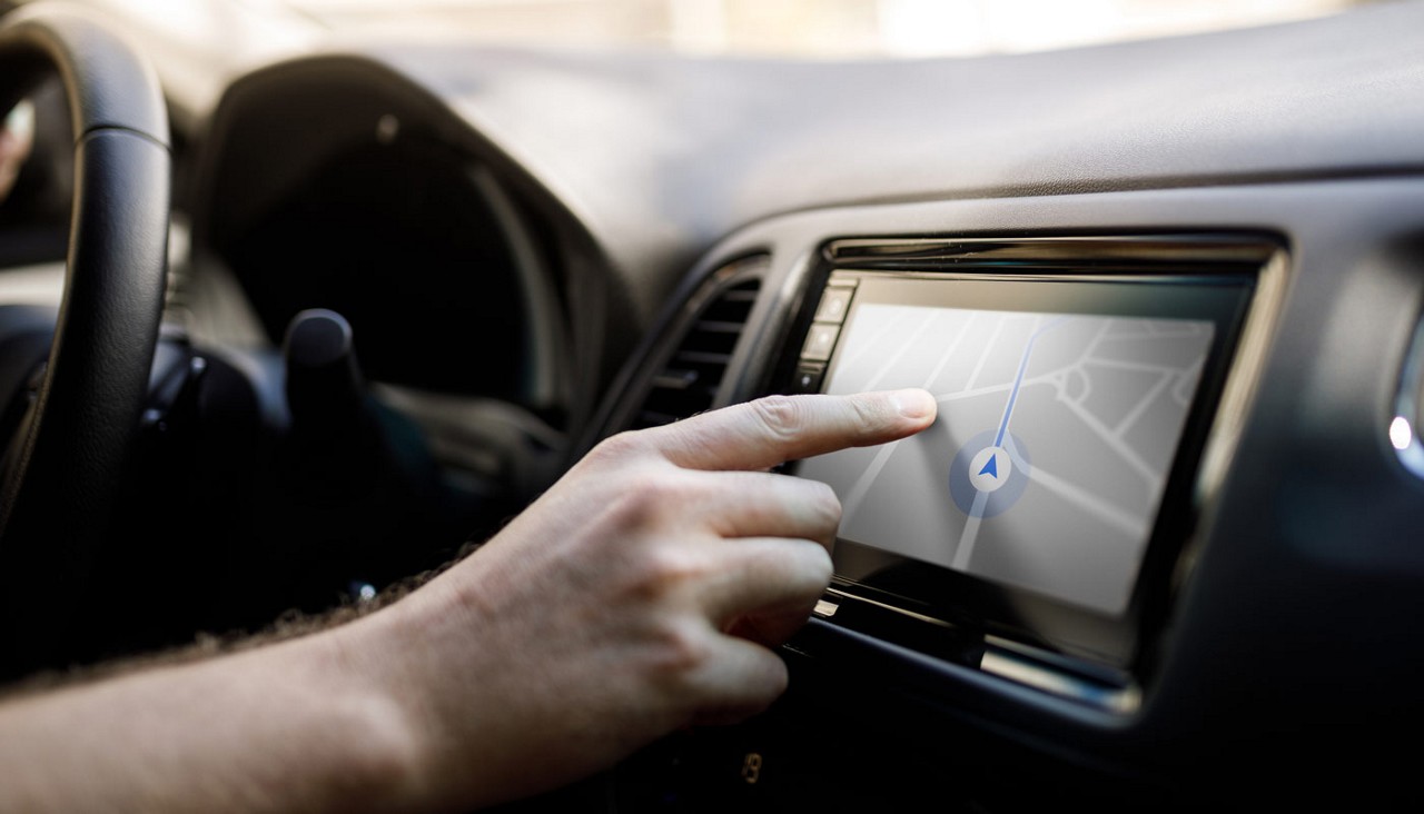 Close up view of a person programming a trip route into a car's dashboard video mapping system.