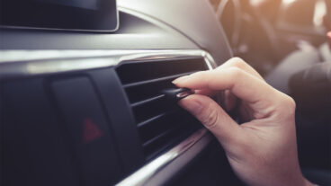 Close up view of a person adjusting the air flow of dashboard vents.