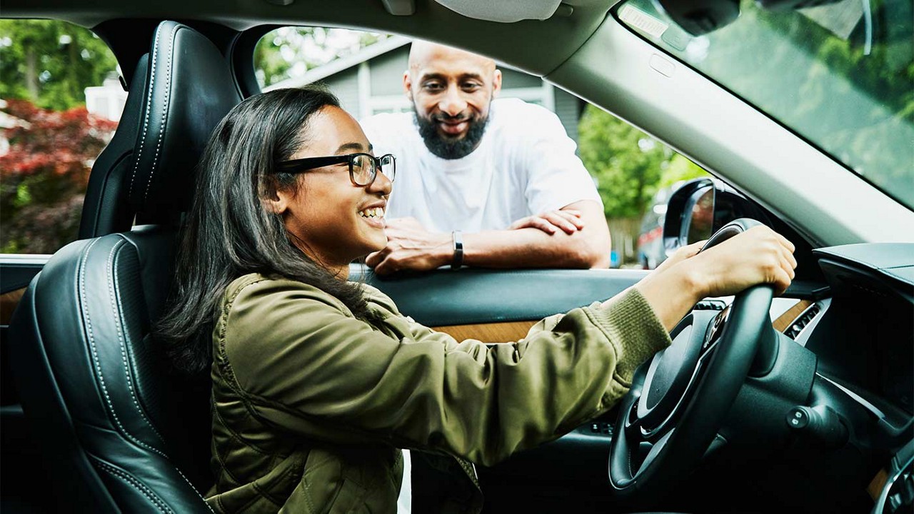 A father watching his daughter start to drive for the first time.