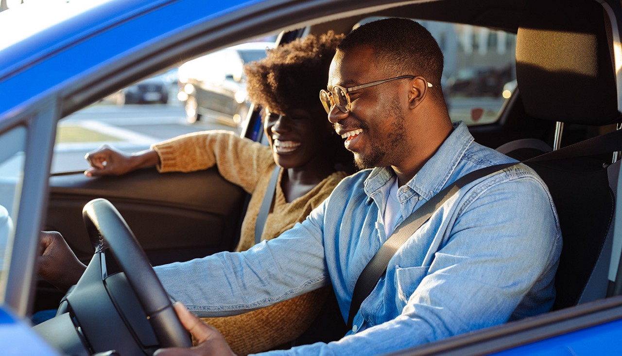 A couple sitting in the front seat of a car preparing to drive away.