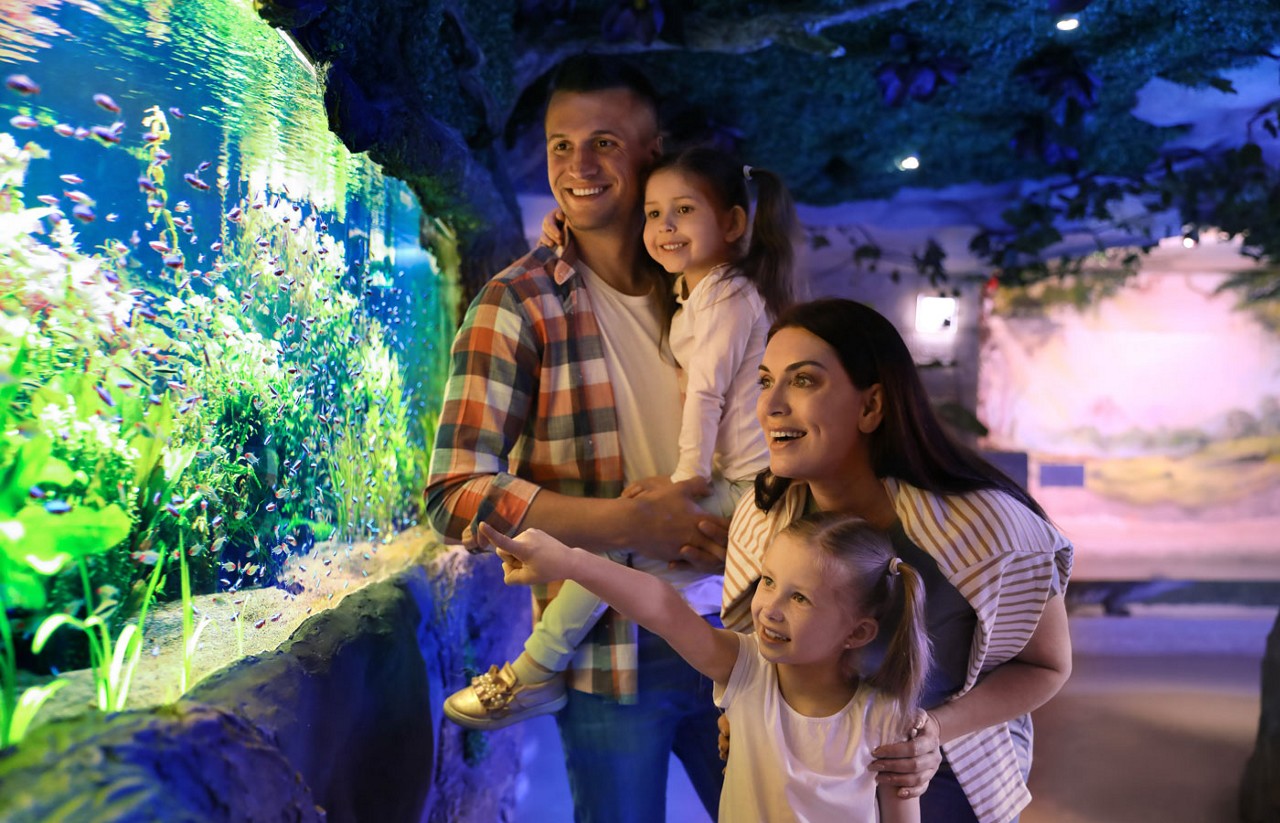 Happy family near aquarium in oceanarium.