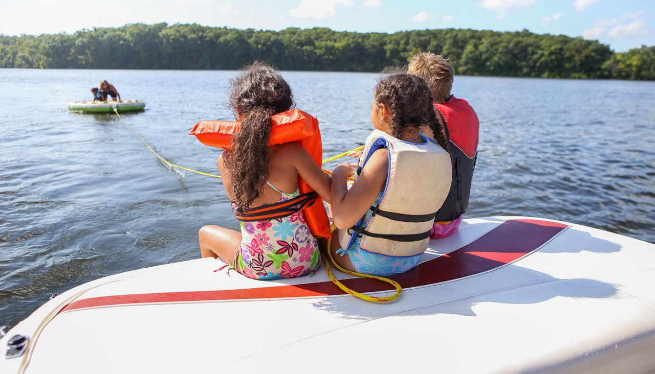 People sitting on a boat and tubing on an inland lake