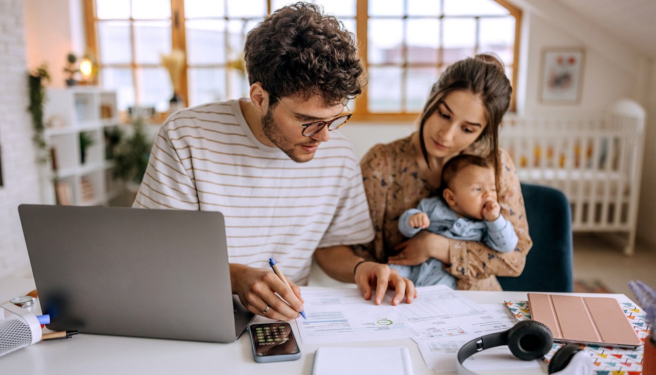 Young family with cute little baby boy going over finances at home