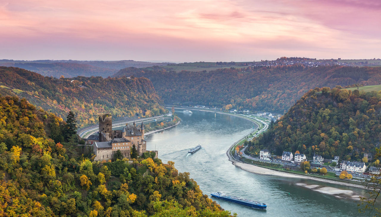 An aerial view of a beautiful river in Europe with purple and pink clouds above.