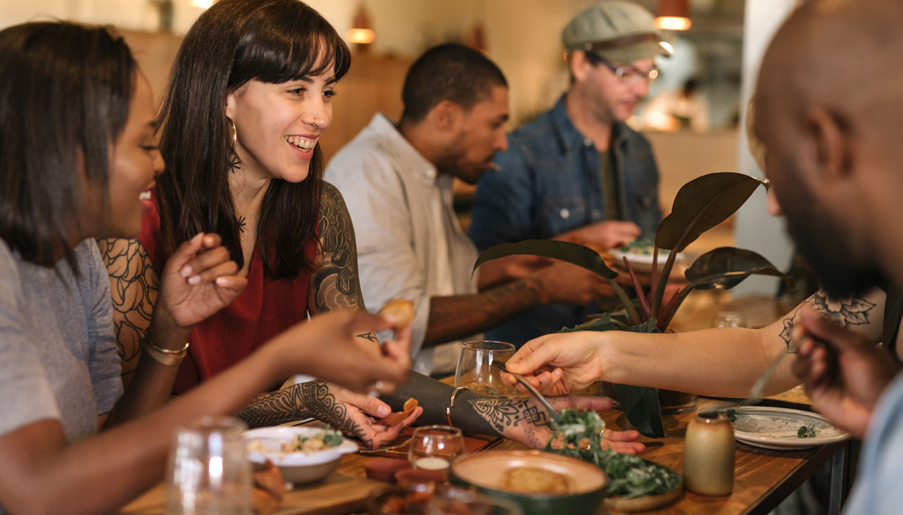 Smiling young friends enjoying dinner together in a trendy bistro