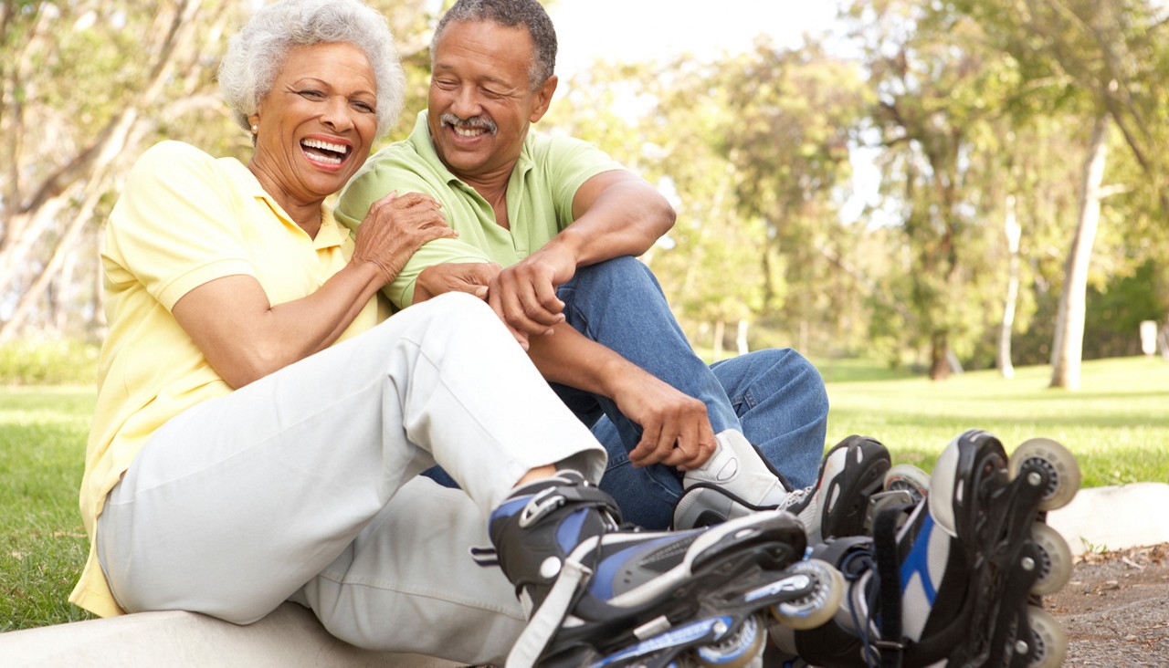 Senior couple putting on inline skates in park