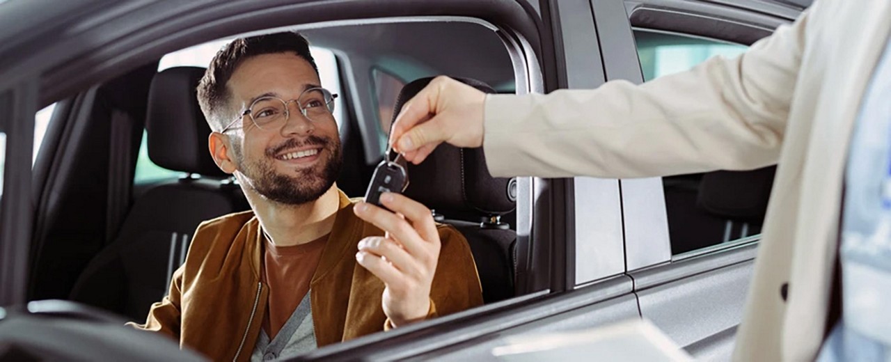 A man accepting a key to his car from a car rental agent