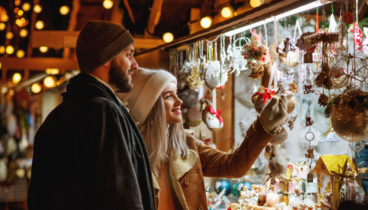 A young couple wearing winter clothes looking at decorations at a Christmas Market
